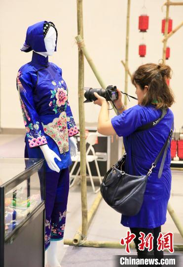 在23日开幕的三亚·中华非遗织绣技艺文化旅游周上，参观者在拍摄展出的服饰。　王晓斌 摄